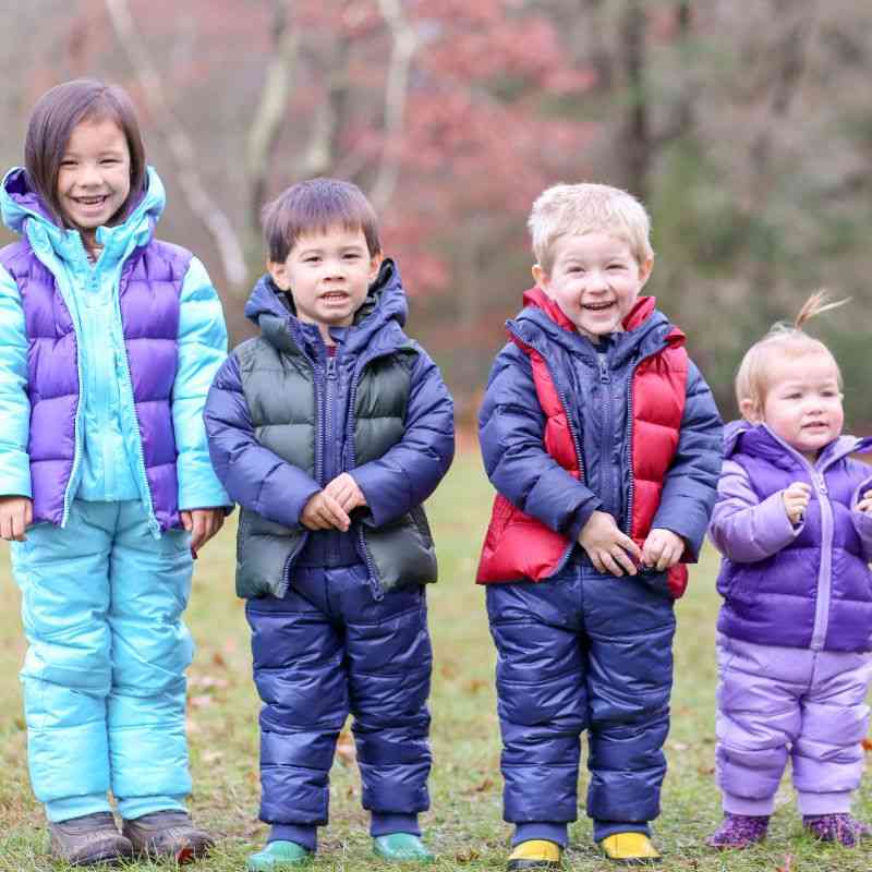 a group of young children standing next to each other wearing roads coats and matching soft pack-able snow pant.