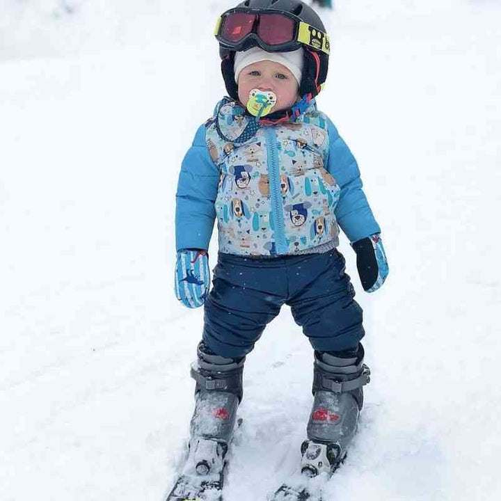 Child wearing navy Packable Snow Pants and a light blue Road Coat, playing in the snow, highlighting warmth and comfort.