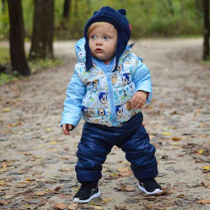 Child wearing navy Packable Snow Pants and blue Road Coat, walking through a park, showcasing the pants’ versatility and warmth.