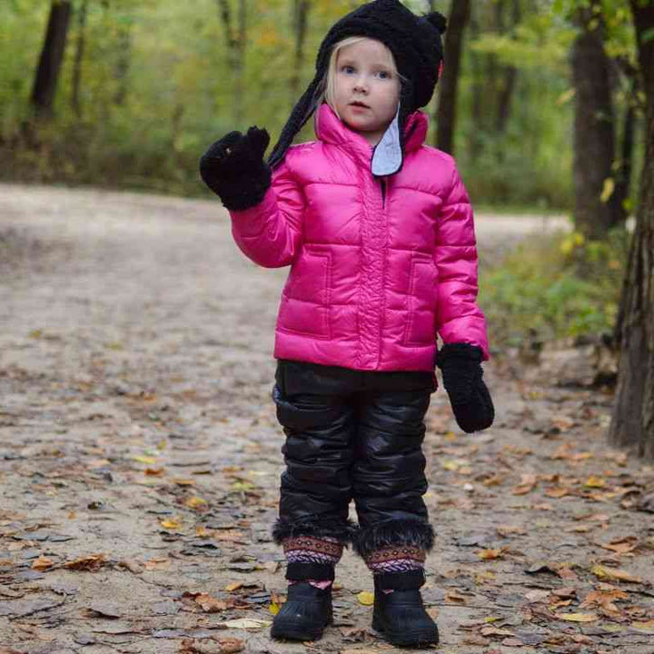 Child wearing black Packable Snow Pants and pink Road Coat walking through a park, highlighting versatility and style in winter weather.