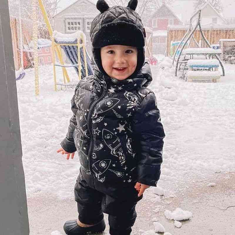 Little Boy wearing the One Kid Quilted Bomber hat in black with matching Road Coat and soft pack-able snow pant.