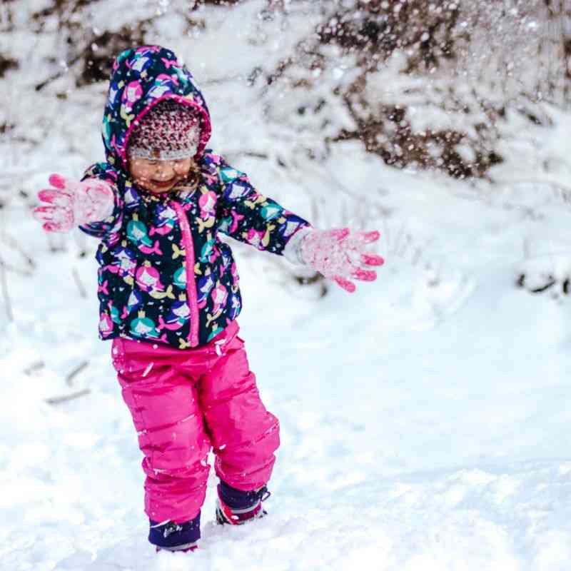 Child wearing fuchsia Packable Snow Pants and Road Coat, playing in the snow, highlighting warmth and vibrant style.