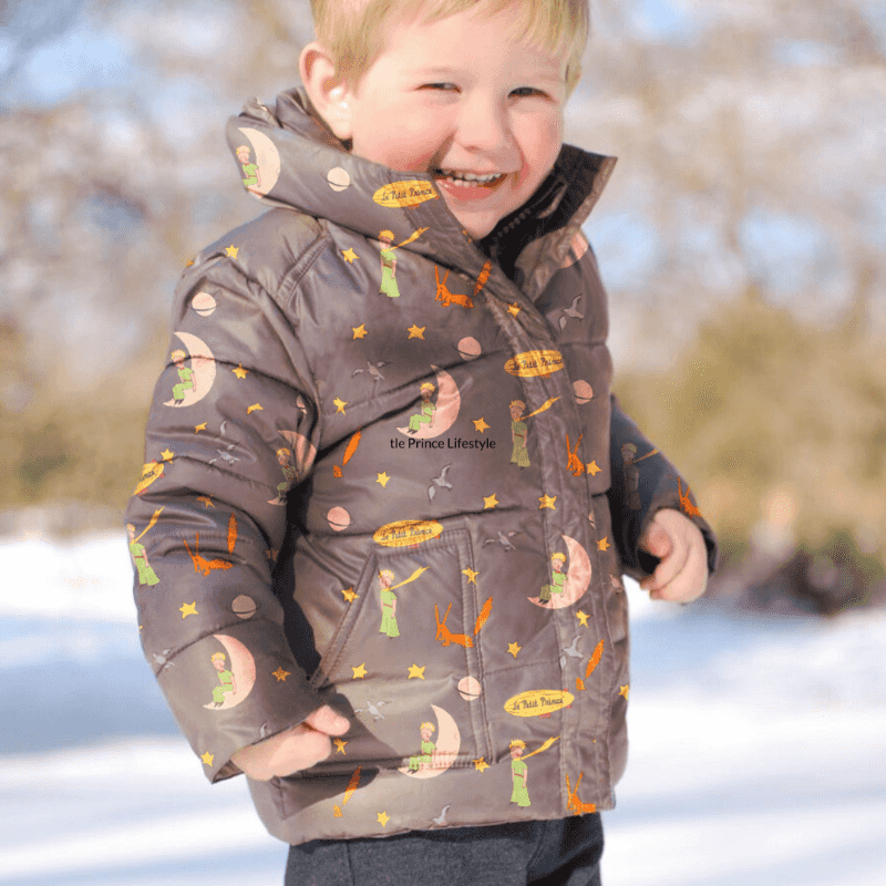Child wearing a Road Coat with a Little Prince pattern, smiling outdoors in the snow